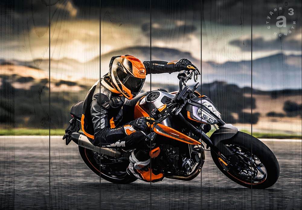 Мотоциклист едущий боком на мотоцикле Duke по трассе на фоне гор и природы, оранжевый, мотоспорт